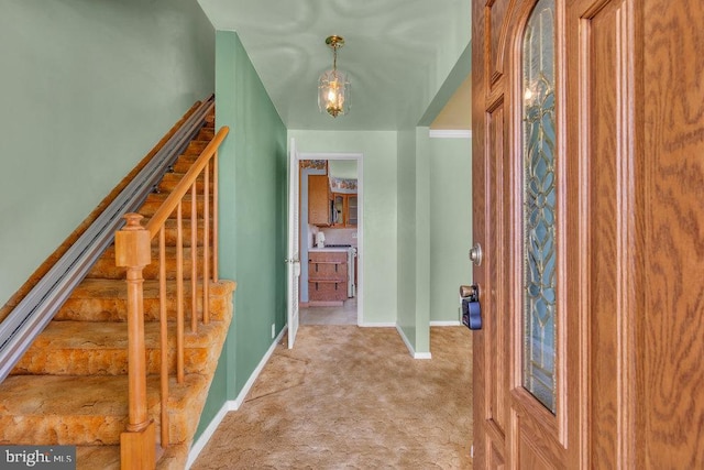 foyer with light colored carpet, baseboards, and stairway