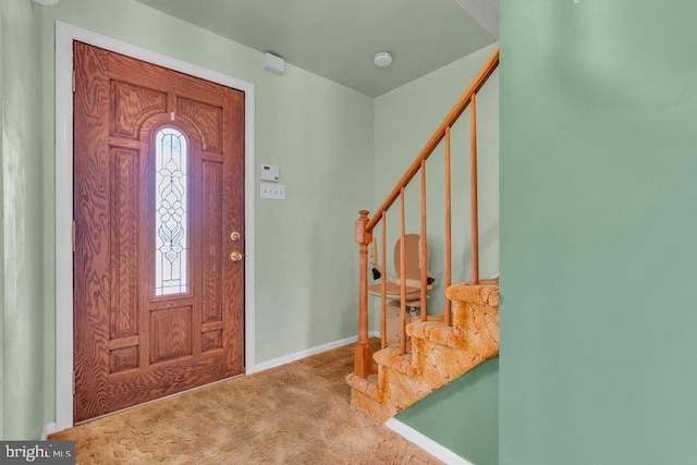 foyer entrance featuring carpet flooring, baseboards, and stairway