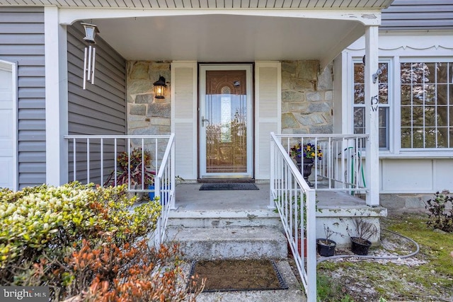 view of exterior entry with a porch and stone siding