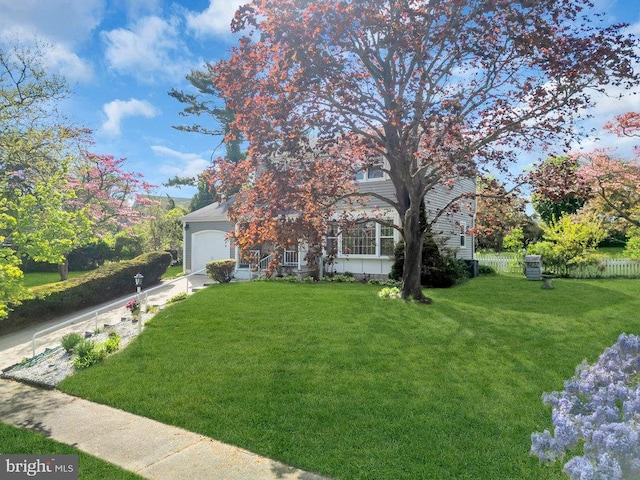 obstructed view of property featuring fence, an attached garage, driveway, and a front yard