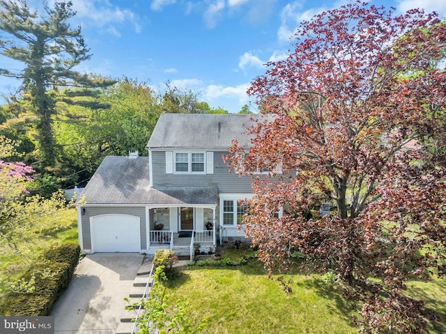 view of front of property with covered porch, a front yard, concrete driveway, an attached garage, and a shingled roof