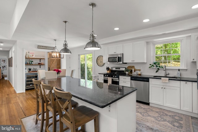 kitchen with a kitchen island, a sink, white cabinets, stainless steel appliances, and recessed lighting