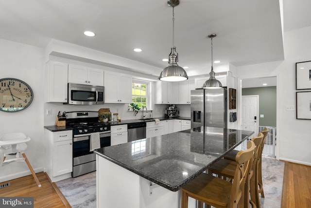 kitchen with a kitchen breakfast bar, white cabinetry, baseboards, stainless steel appliances, and light wood-style flooring