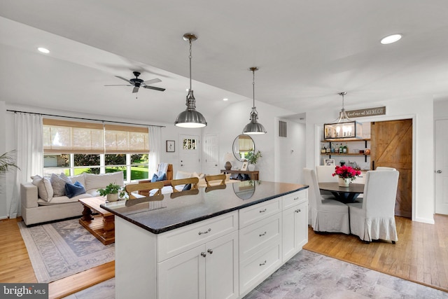 kitchen with a ceiling fan, white cabinets, open floor plan, and hanging light fixtures