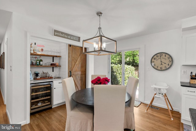 dining room featuring visible vents, wine cooler, bar, light wood finished floors, and a notable chandelier