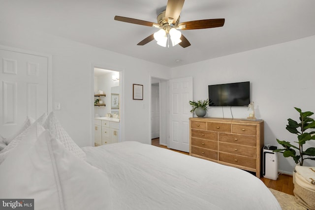 bedroom featuring connected bathroom, a ceiling fan, baseboards, and wood finished floors