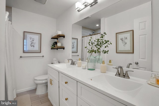 full bathroom with double vanity, toilet, a sink, and wood finished floors