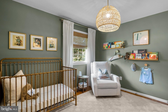 bedroom featuring baseboards, a notable chandelier, and a crib