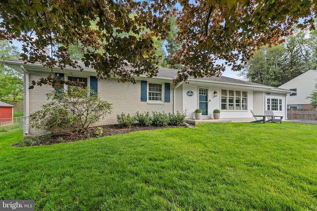 ranch-style home featuring fence, a front lawn, and brick siding