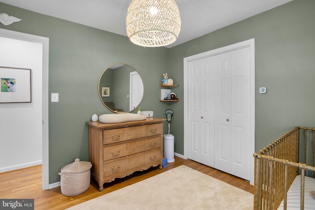 bedroom with a closet, baseboards, wood finished floors, and a notable chandelier