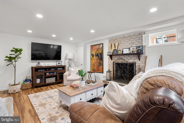 living room with a brick fireplace, recessed lighting, baseboards, and wood finished floors