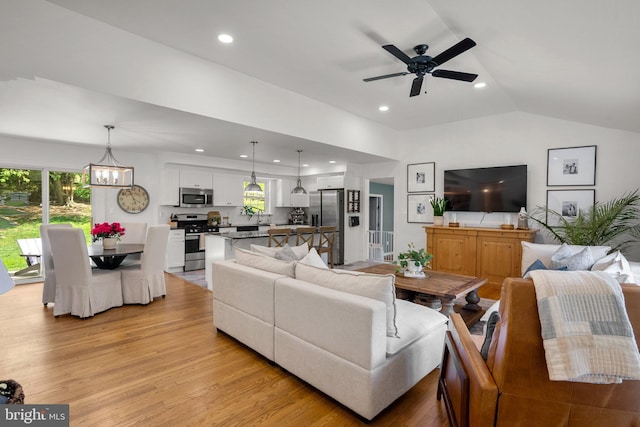 living area with recessed lighting, light wood finished floors, ceiling fan with notable chandelier, and lofted ceiling