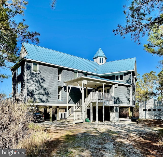 rear view of property featuring covered porch, stairway, metal roof, and dirt driveway