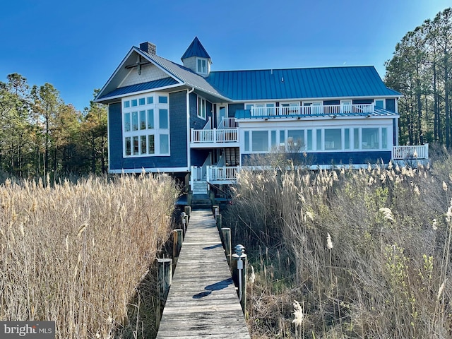 rear view of property with metal roof, a balcony, and a standing seam roof
