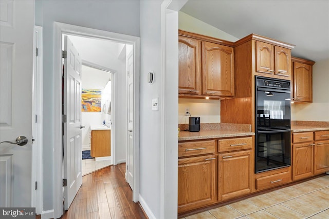 2725 Baublitz Rd, Owings Mills, MD 21117 - kitchen with dobule oven black, brown cabinetry, baseboards, and lofted ceiling