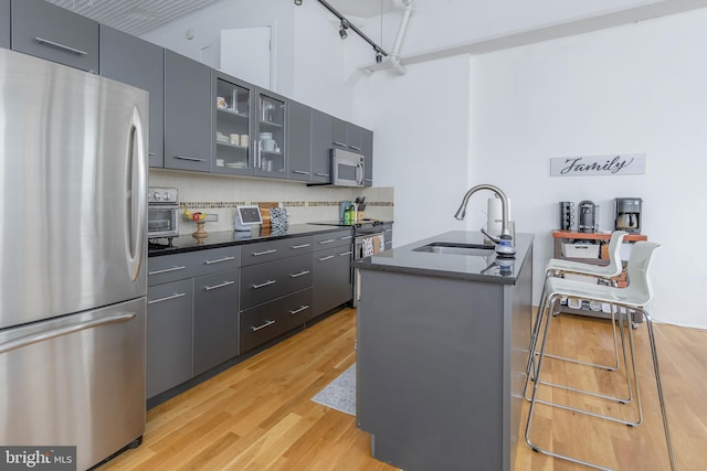 2200 Arch St Unit 514, Philadelphia, PA 19103 - kitchen with glass insert cabinets, light wood-style flooring, a sink, dark countertops, and stainless steel appliances
