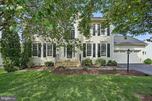 colonial-style house featuring a garage, driveway, and a front lawn