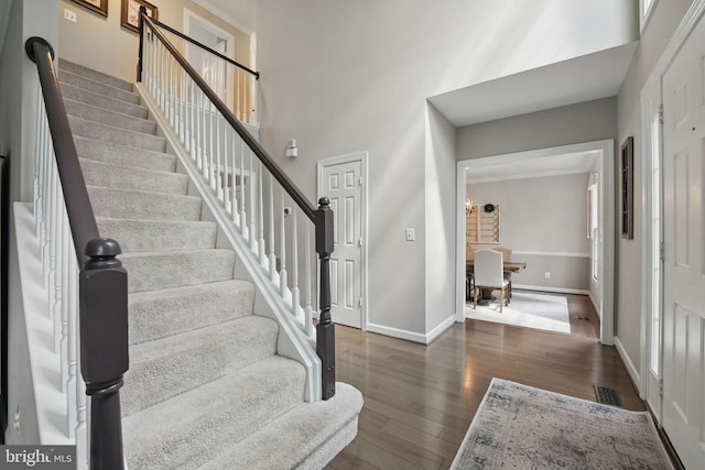 entryway featuring baseboards, wood finished floors, visible vents, and stairway