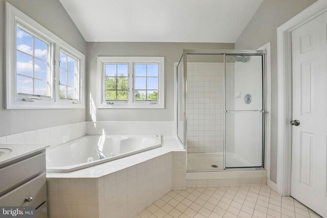 bathroom with tile patterned flooring, vanity, lofted ceiling, a bath, and a stall shower
