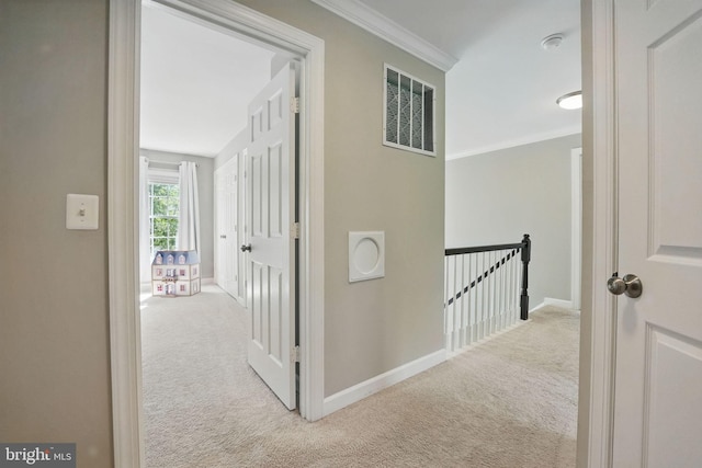 hallway with visible vents, crown molding, carpet floors, baseboards, and an upstairs landing