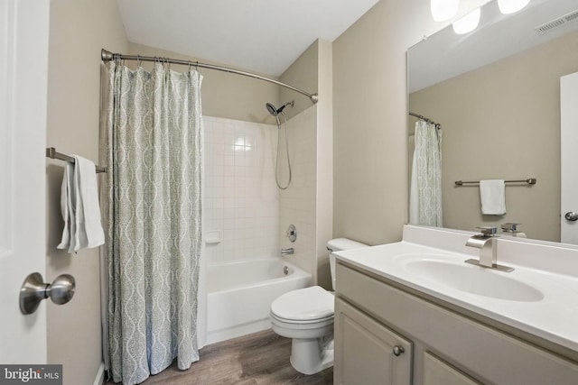 bathroom with vanity, toilet, wood finished floors, shower / tub combo, and visible vents