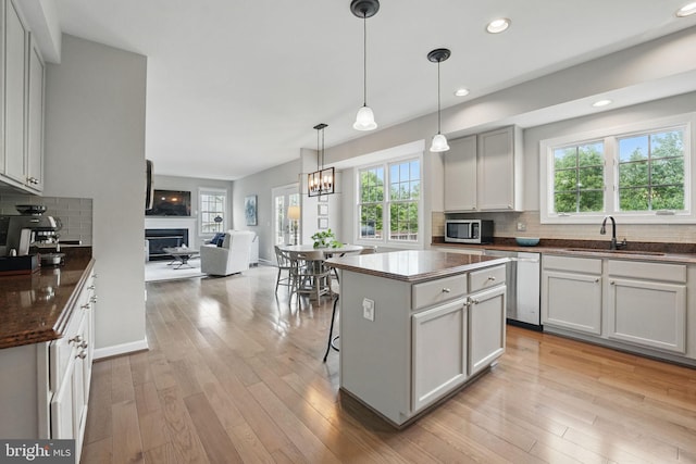 kitchen with a sink, tasteful backsplash, a fireplace, and stainless steel appliances
