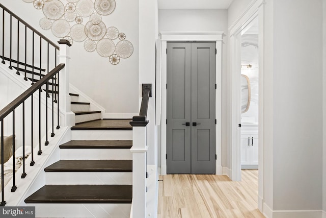 staircase featuring baseboards, a chandelier, and wood finished floors
