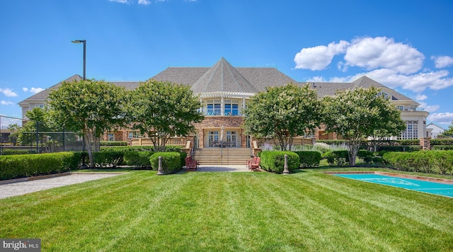 back of house with a lawn, fence, and brick siding