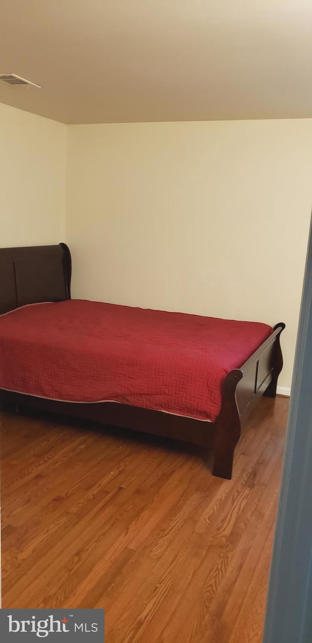 bedroom with visible vents, baseboards, and wood finished floors