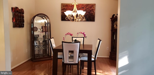 dining space with baseboards, an inviting chandelier, and wood finished floors