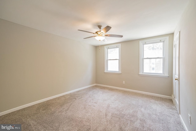 empty room with ceiling fan, light colored carpet, and baseboards