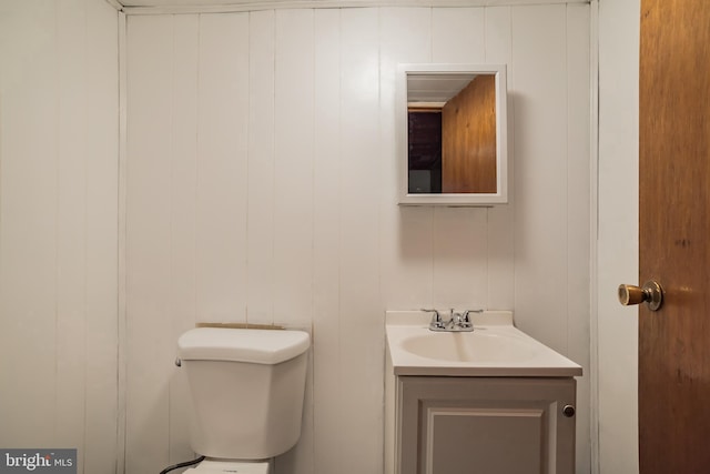 bathroom featuring vanity, a decorative wall, and toilet