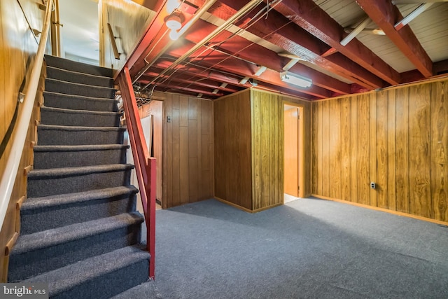 basement featuring stairs, wood walls, and carpet