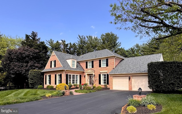 view of front of house with aphalt driveway, an attached garage, brick siding, and a front yard