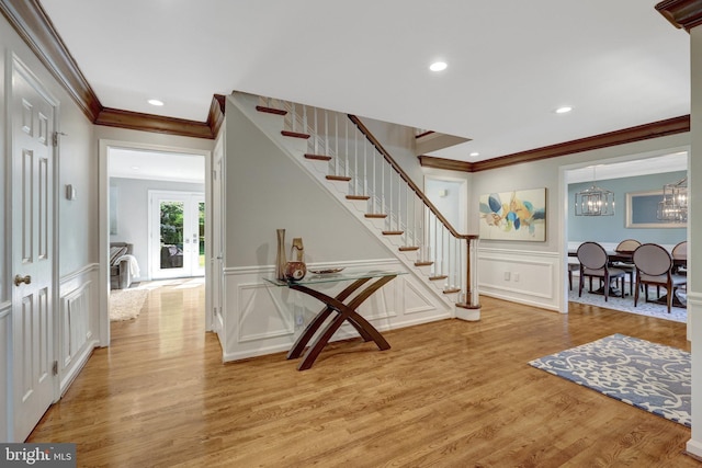 foyer entrance featuring stairs, ornamental molding, light wood finished floors, and a decorative wall