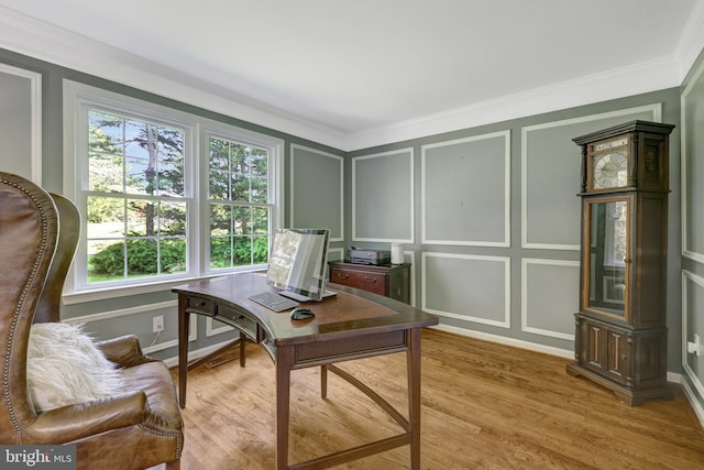 office space with crown molding, baseboards, a decorative wall, and light wood-style flooring