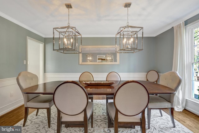 dining area with wainscoting, crown molding, a notable chandelier, and wood finished floors