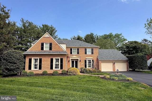 view of front of home featuring driveway, brick siding, an attached garage, and a front yard
