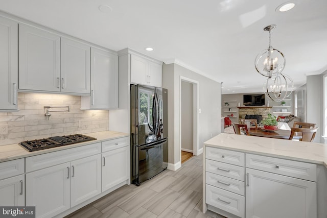 kitchen with baseboards, an inviting chandelier, backsplash, black appliances, and white cabinets