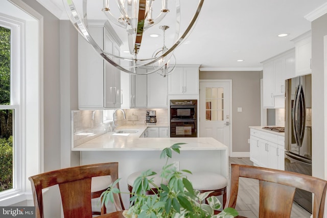 kitchen featuring fridge, an inviting chandelier, a sink, dobule oven black, and backsplash