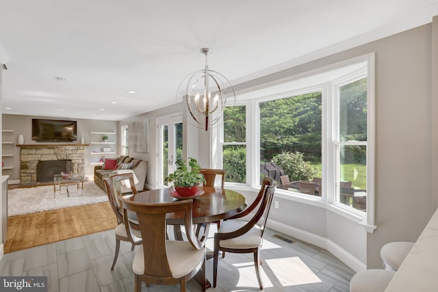 dining space with light tile patterned floors, visible vents, baseboards, a stone fireplace, and a chandelier