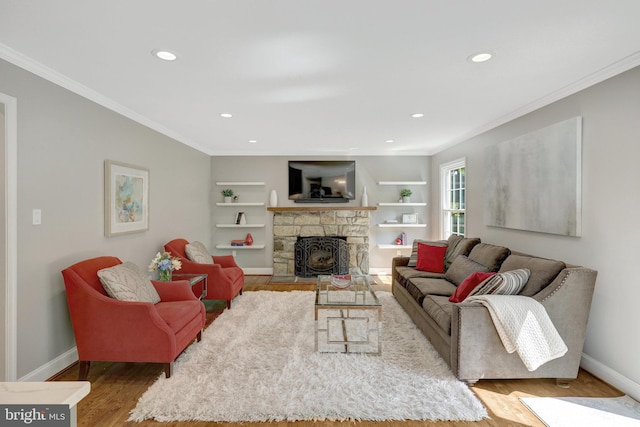 living area with baseboards, a stone fireplace, ornamental molding, and wood finished floors