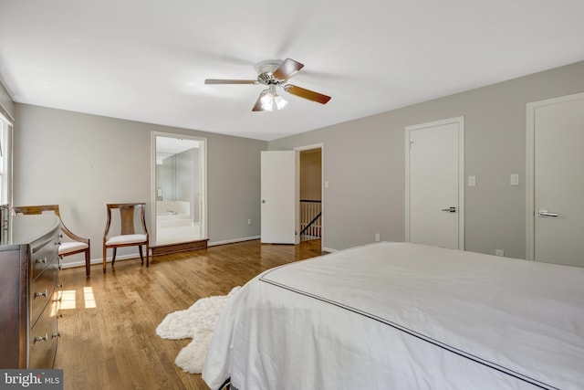 bedroom with ensuite bath, baseboards, a ceiling fan, and wood finished floors