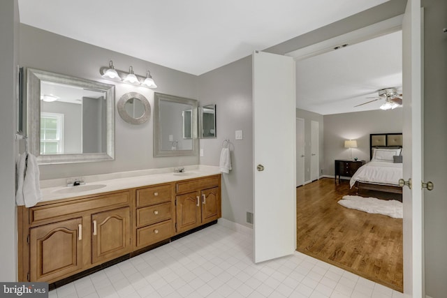 ensuite bathroom with double vanity, connected bathroom, a ceiling fan, and a sink