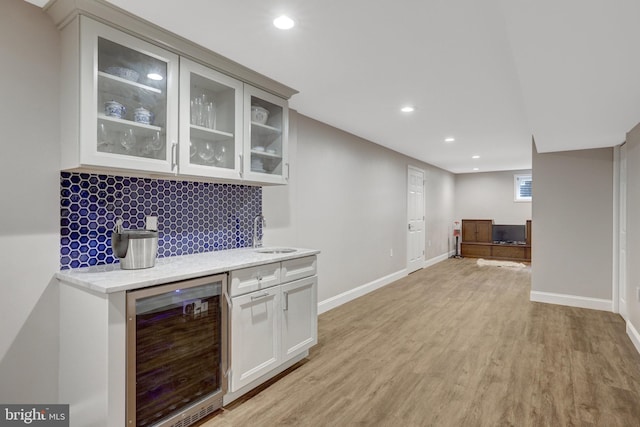 bar featuring wine cooler, light wood finished floors, recessed lighting, and a sink