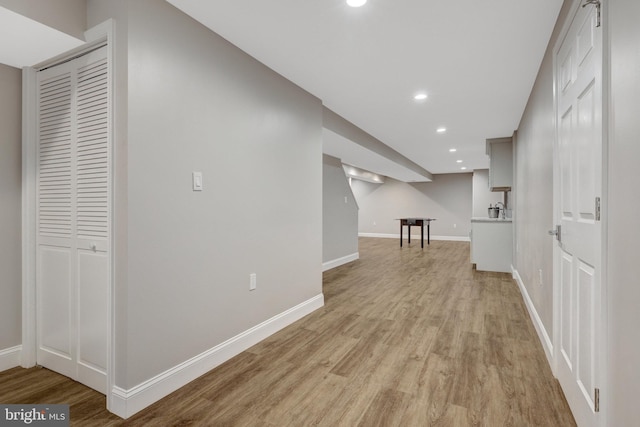 hall with light wood-style floors, baseboards, and recessed lighting