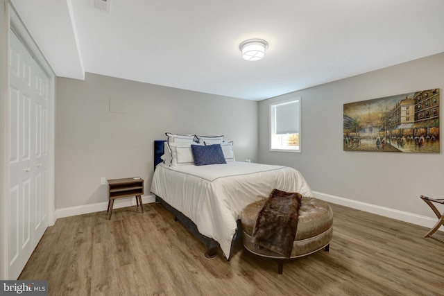 bedroom featuring baseboards, visible vents, and wood finished floors