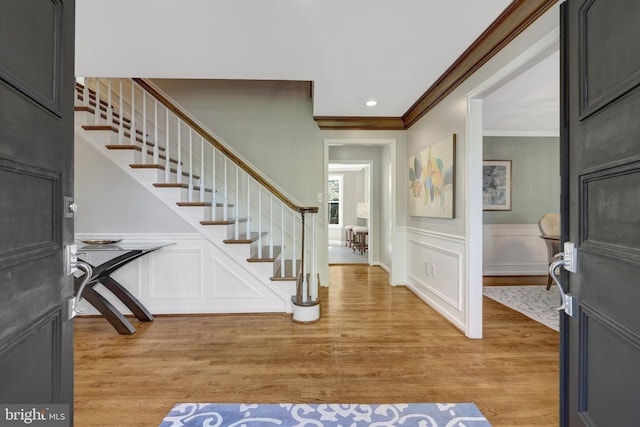 foyer entrance with stairs, a wainscoted wall, light wood-type flooring, recessed lighting, and crown molding