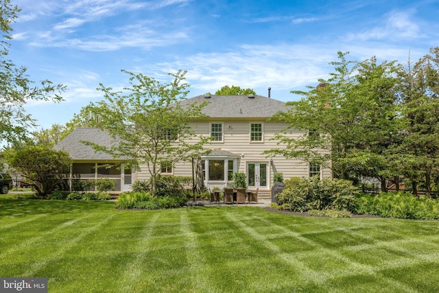 rear view of property with a sunroom, a yard, french doors, and a patio area