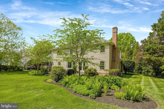 exterior space with central AC, a chimney, and a lawn